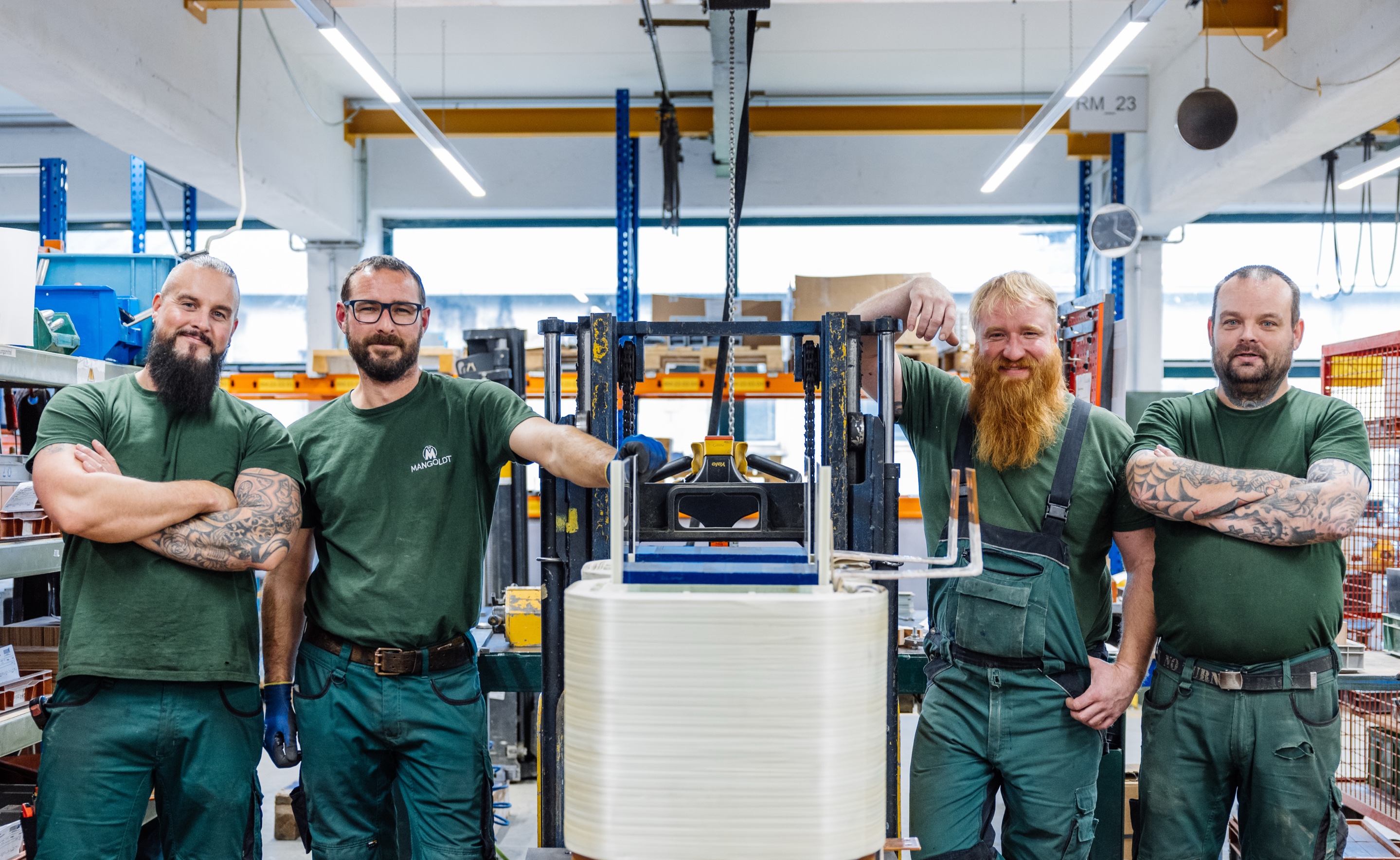 Team of four happy production workers in the workshop look at the camera